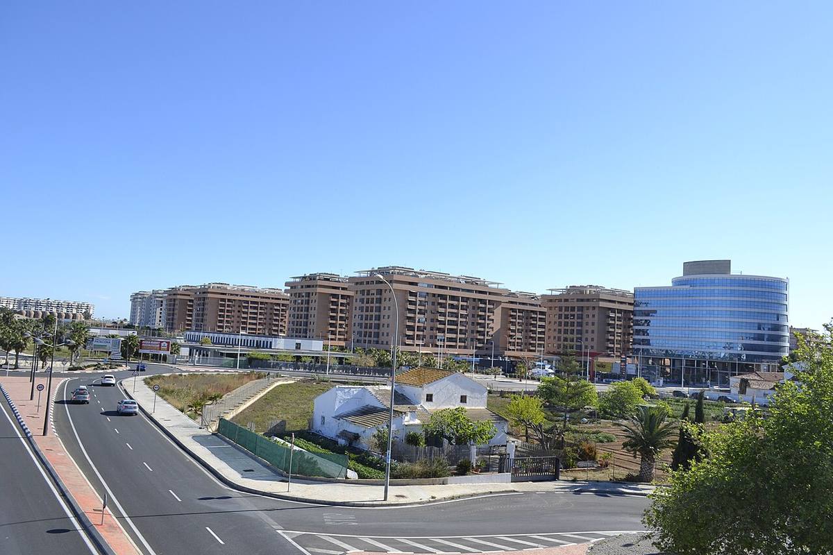Contraste entre una alquería tradicional y edificios de viviendas modernos en Valencia.