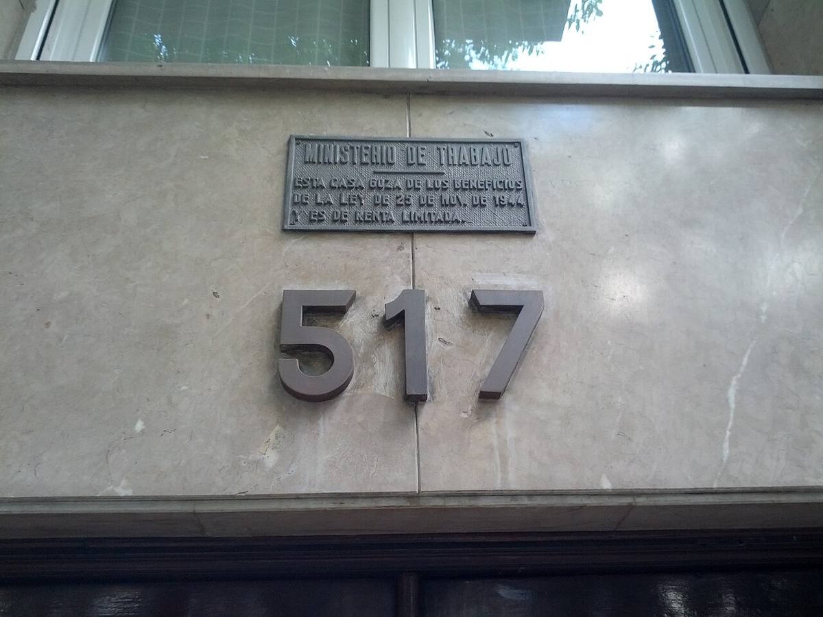 Placa del Ministerio de Trabajo sobre beneficios de renta limitada en un edificio.