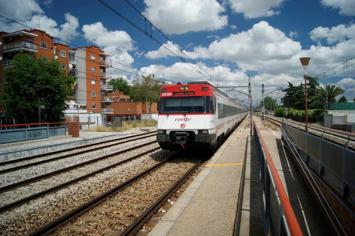 Tren de Renfe a su paso por Torrejón de Ardoz, con bloques de viviendas al fondo.