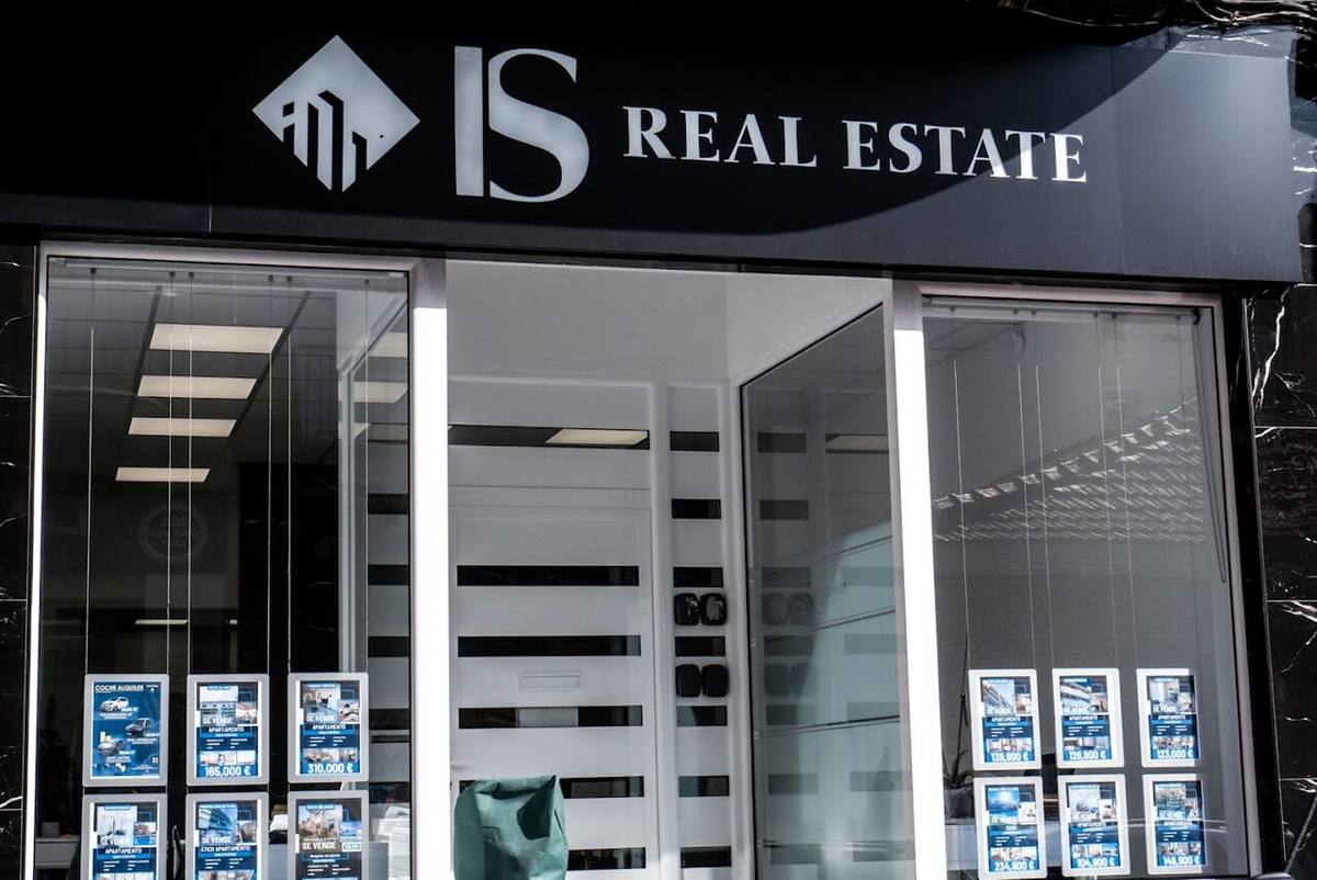 Fachada de una oficina inmobiliaria con anuncios de viviendas en venta.