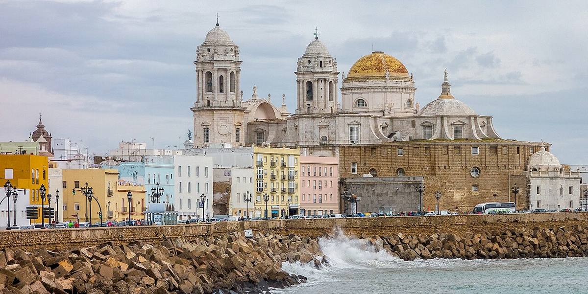 Fachada marítima de Cádiz con la Catedral y edificios de viviendas frente al muelle.