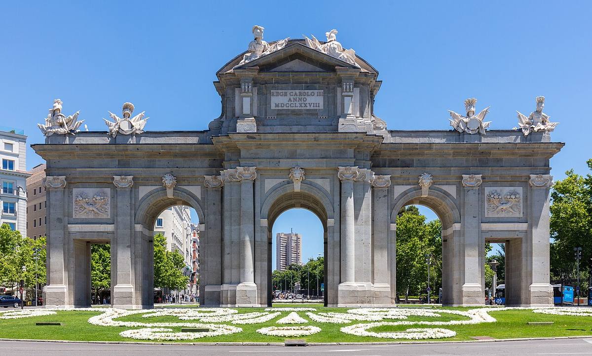 Vista frontal de la Puerta de Alcalá y sus jardines en Madrid.