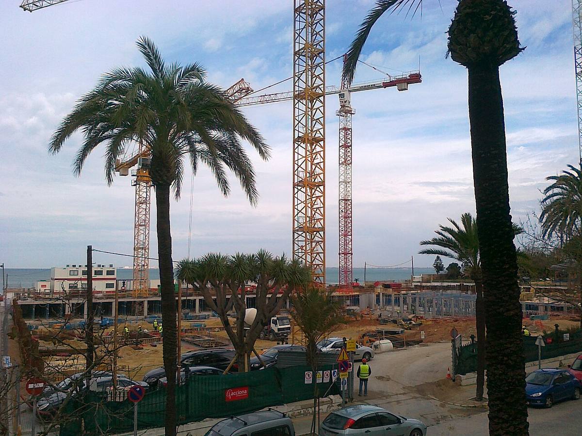 Grúas de construcción en una zona urbana de Cádiz frente al mar.