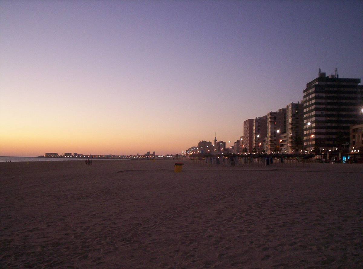 Edificios de viviendas frente a la playa de la Victoria al atardecer.