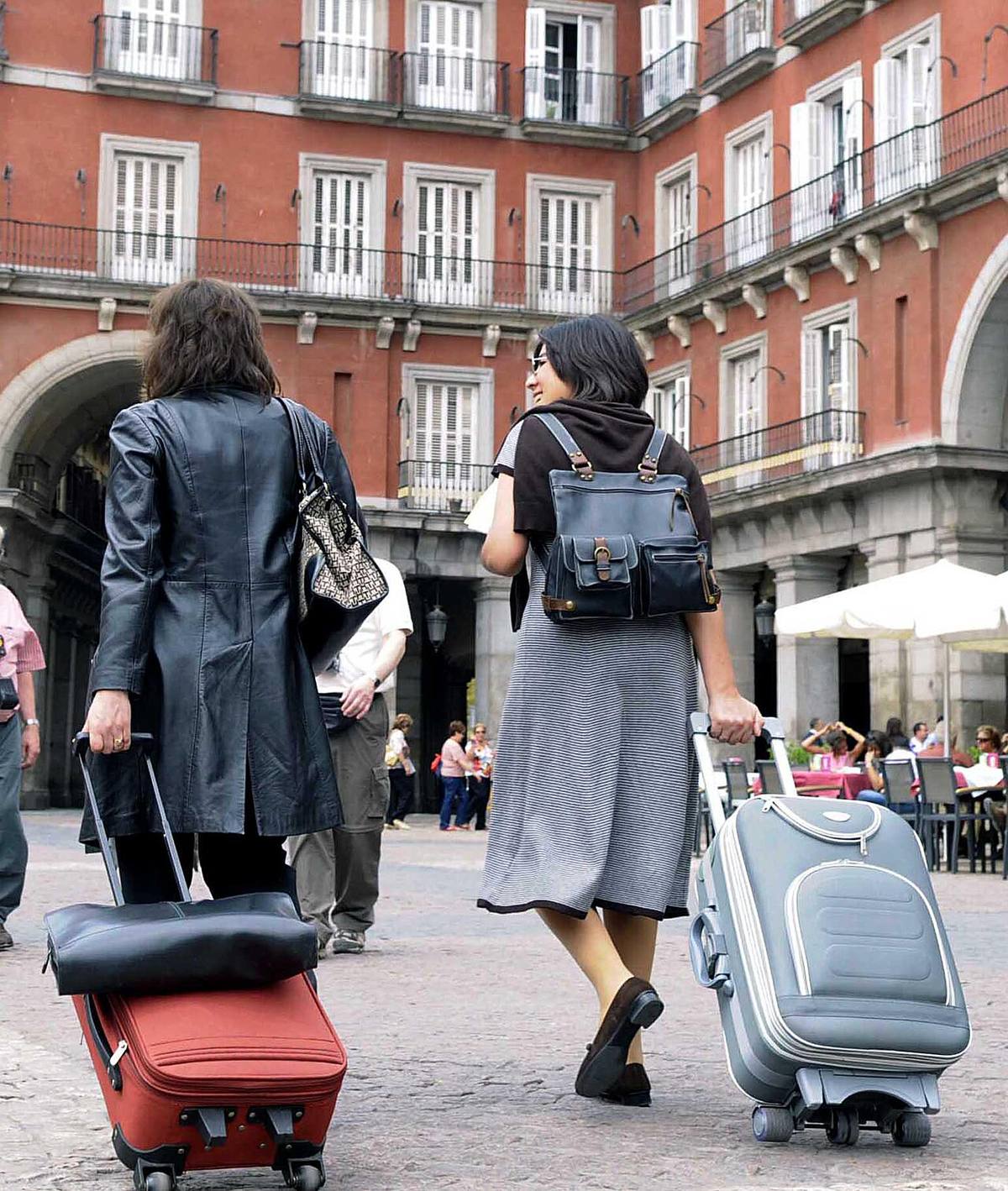 Turistas con maletas frente a edificios de viviendas en la Plaza Mayor de Madrid.
