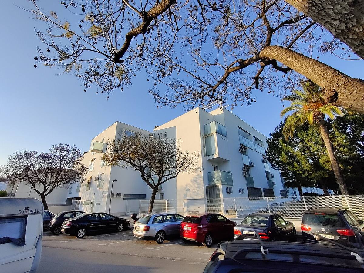 Bloque de viviendas de reciente construcción con zona de aparcamiento.