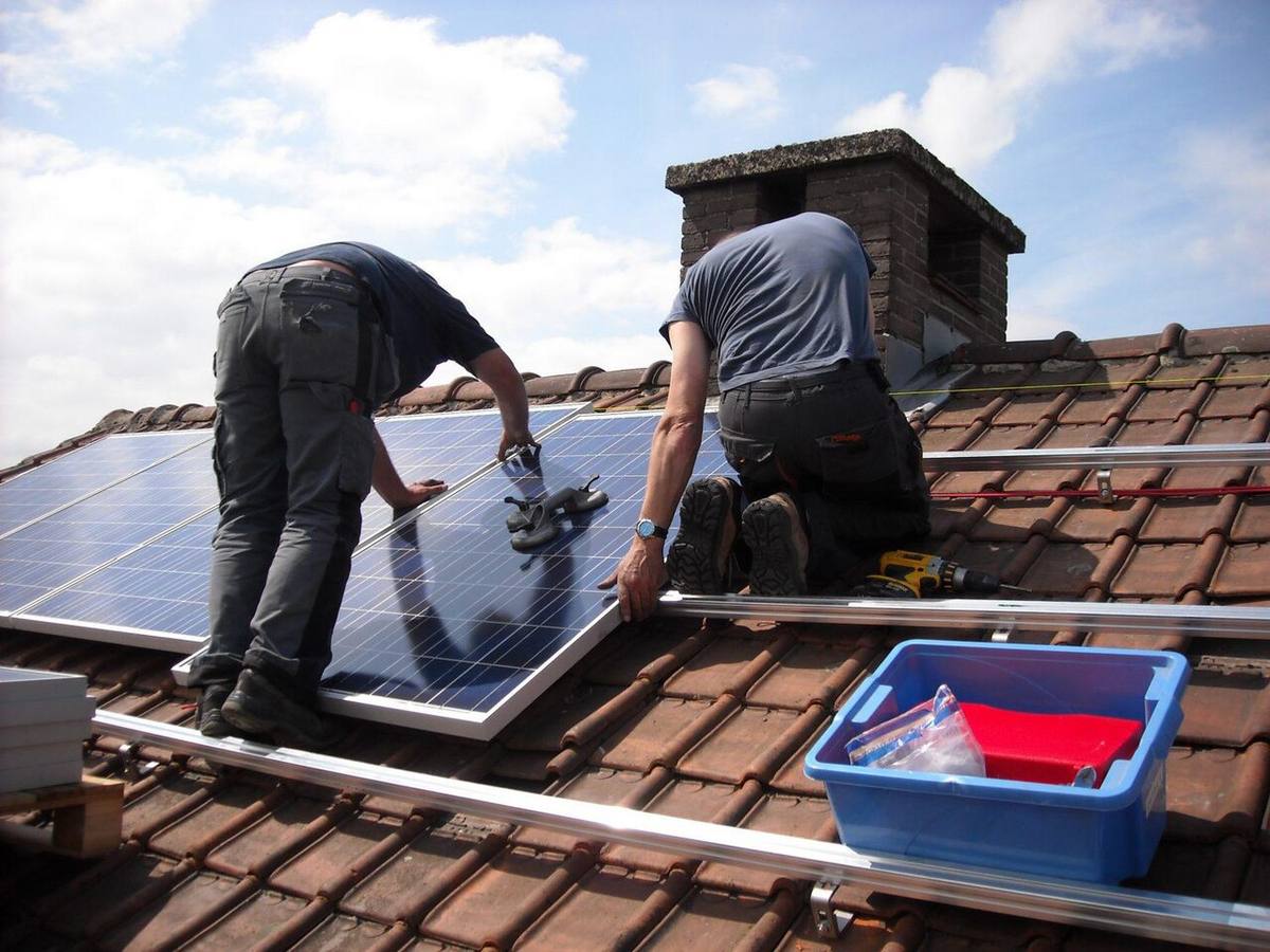 Operarios instalando paneles fotovoltaicos en una vivienda para mejorar su eficiencia energética.