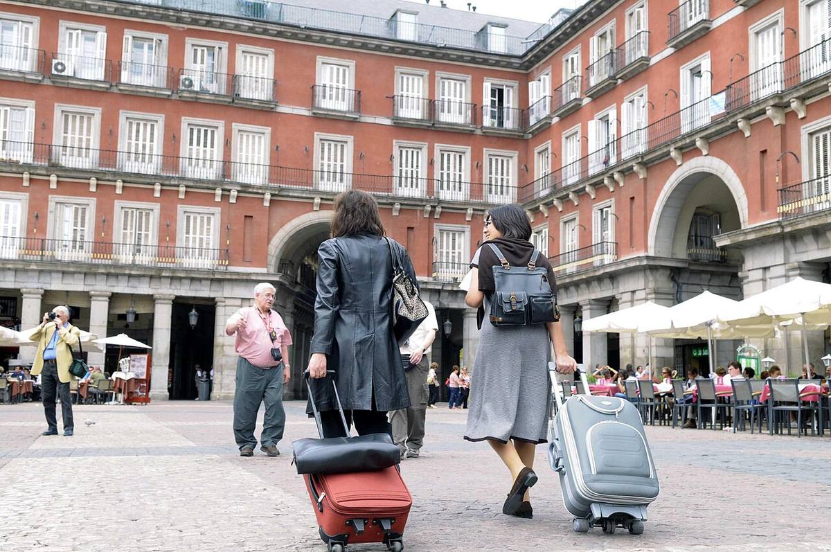 Visitantes con equipaje en una zona de apartamentos turísticos en el centro de Madrid.