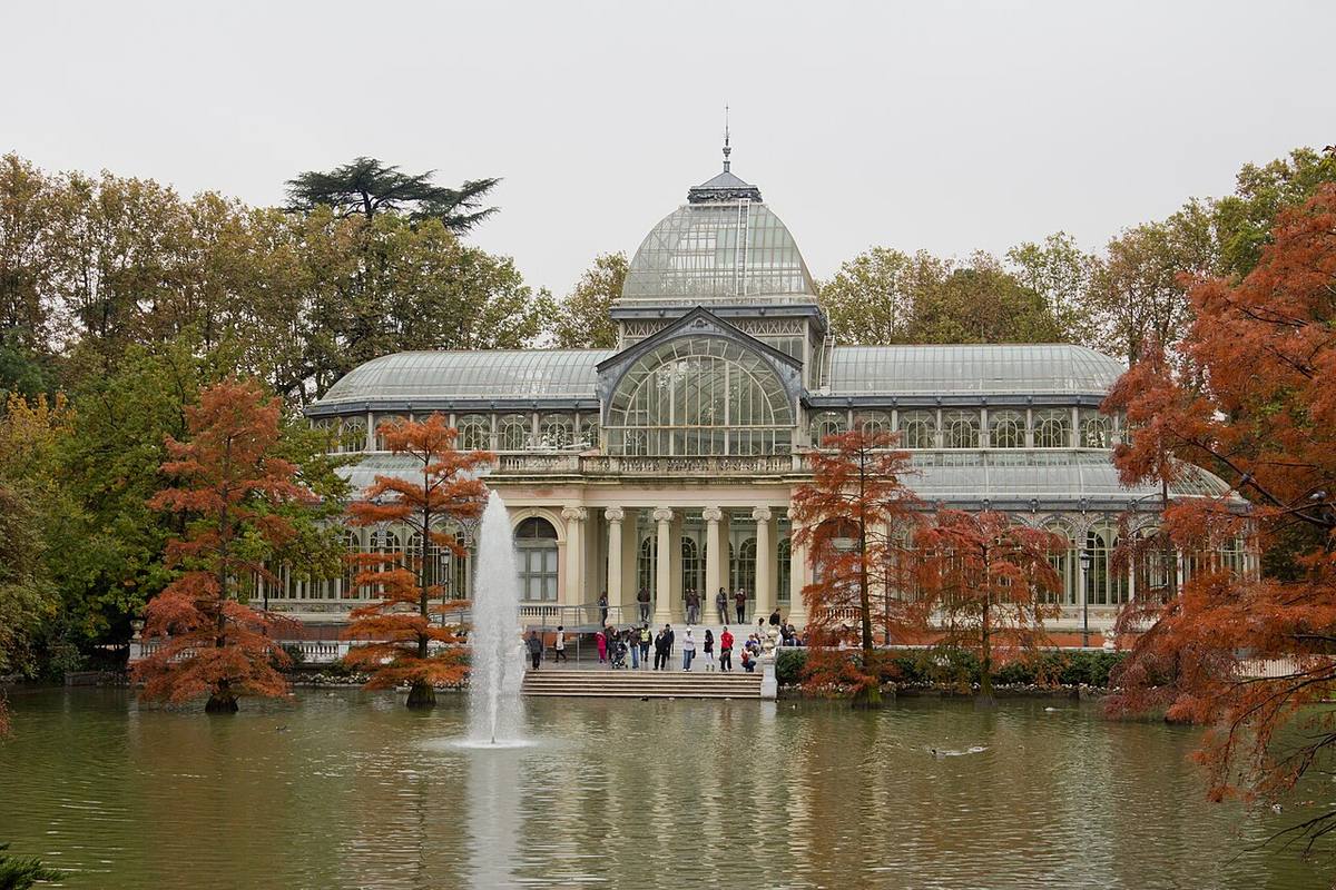 Fachada principal del Palacio de Cristal y estanque en el Parque del Retiro.